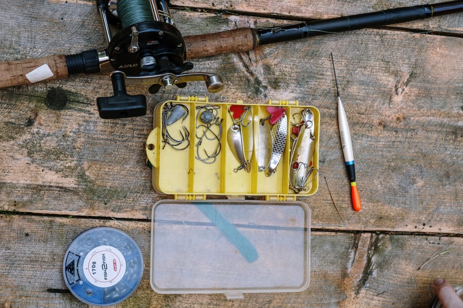 A top-down view of fishing equipment and tackle on a rustic wooden surface.